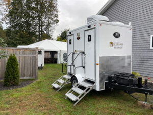 2 stall restroom trailer rental beside a tented wedding reception for guests