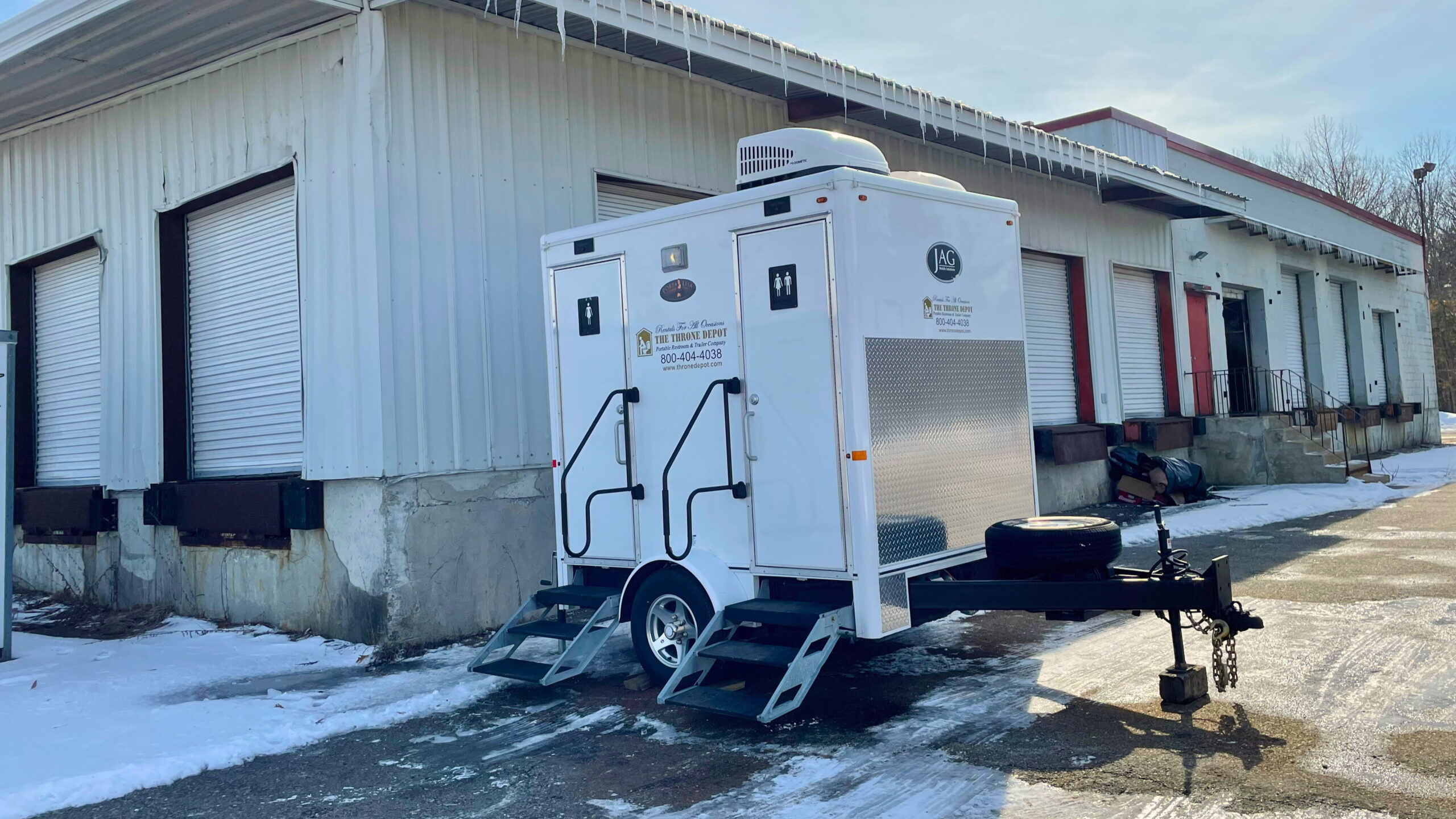 Restroom trailer parked outdoors in winter, undergoing winterizing maintenance