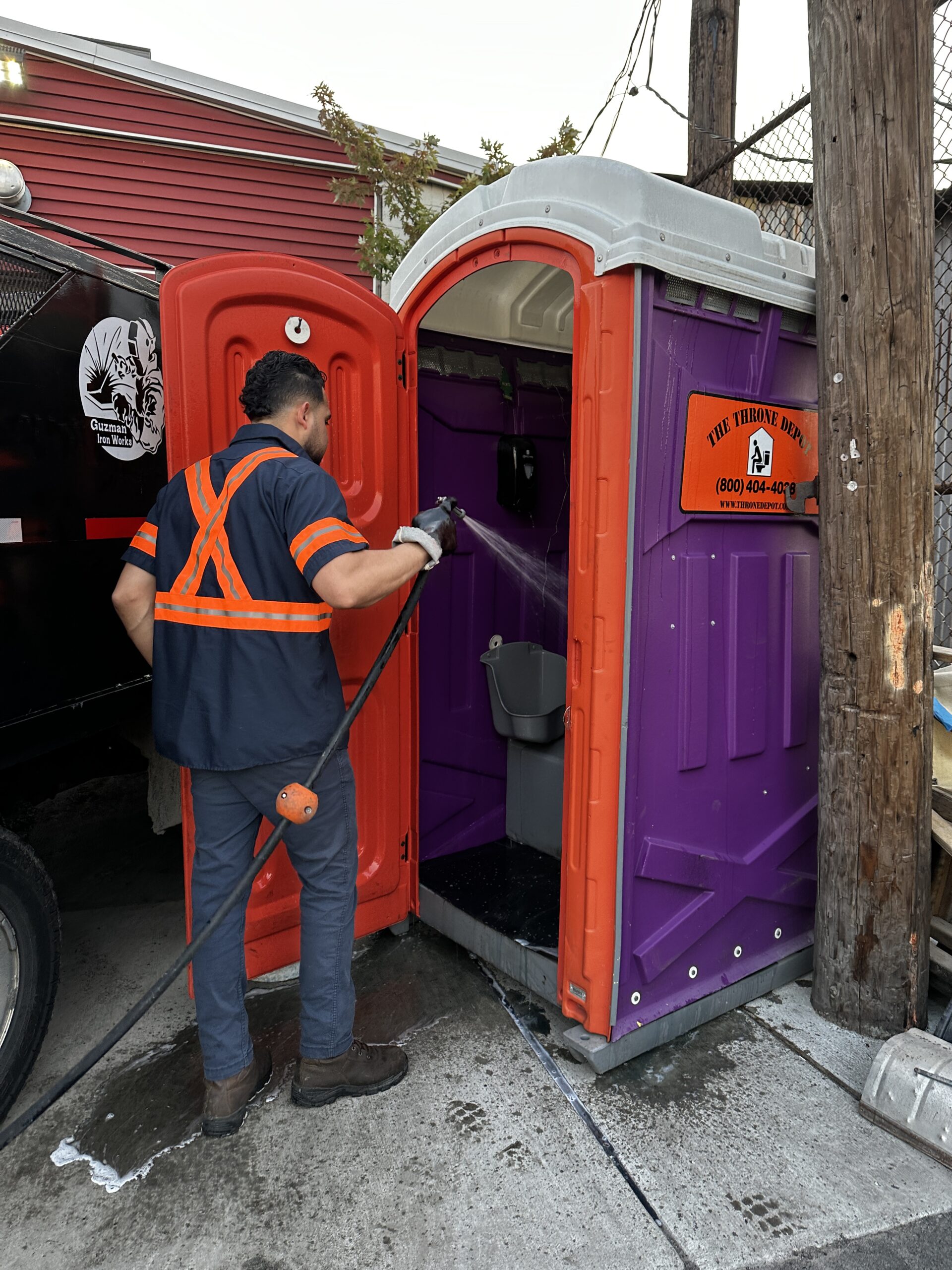 Service technician cleaning and servicing a portable restroom on a job site