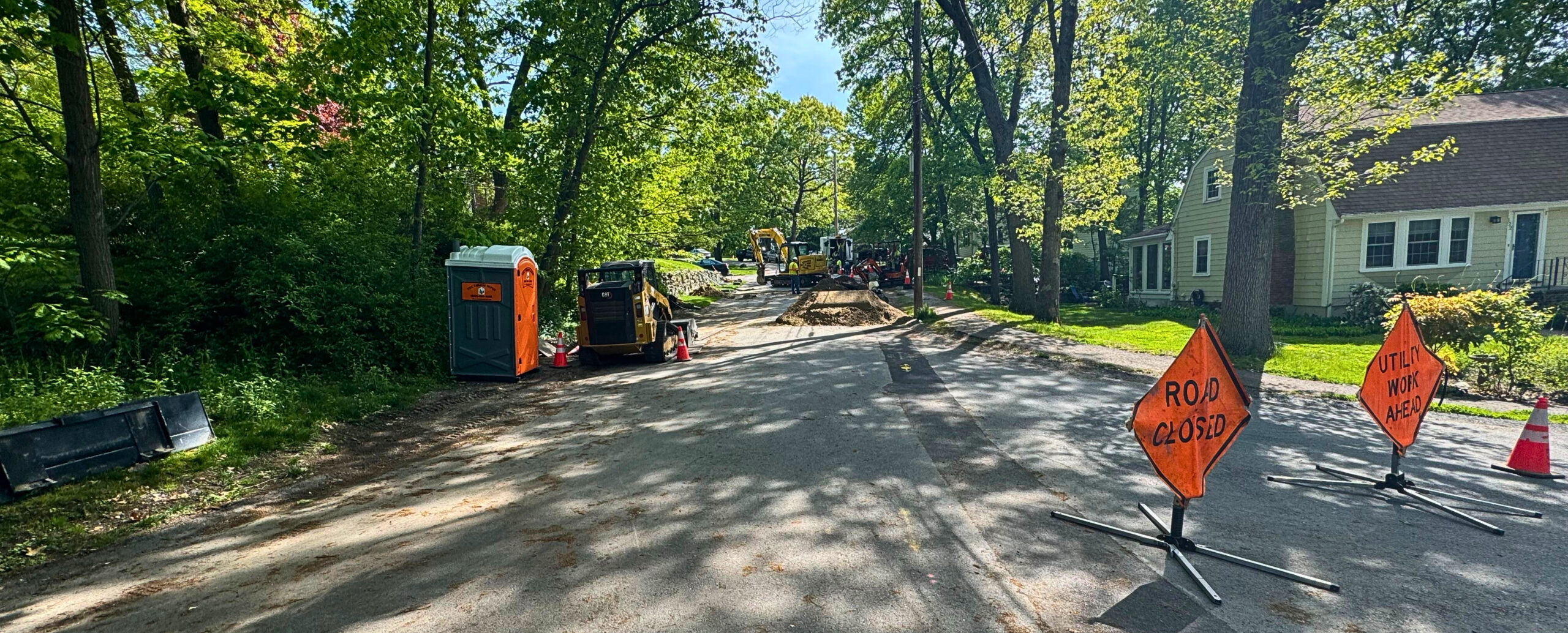 Portable toilet placed on a street during active road construction to support on-site crew productivity