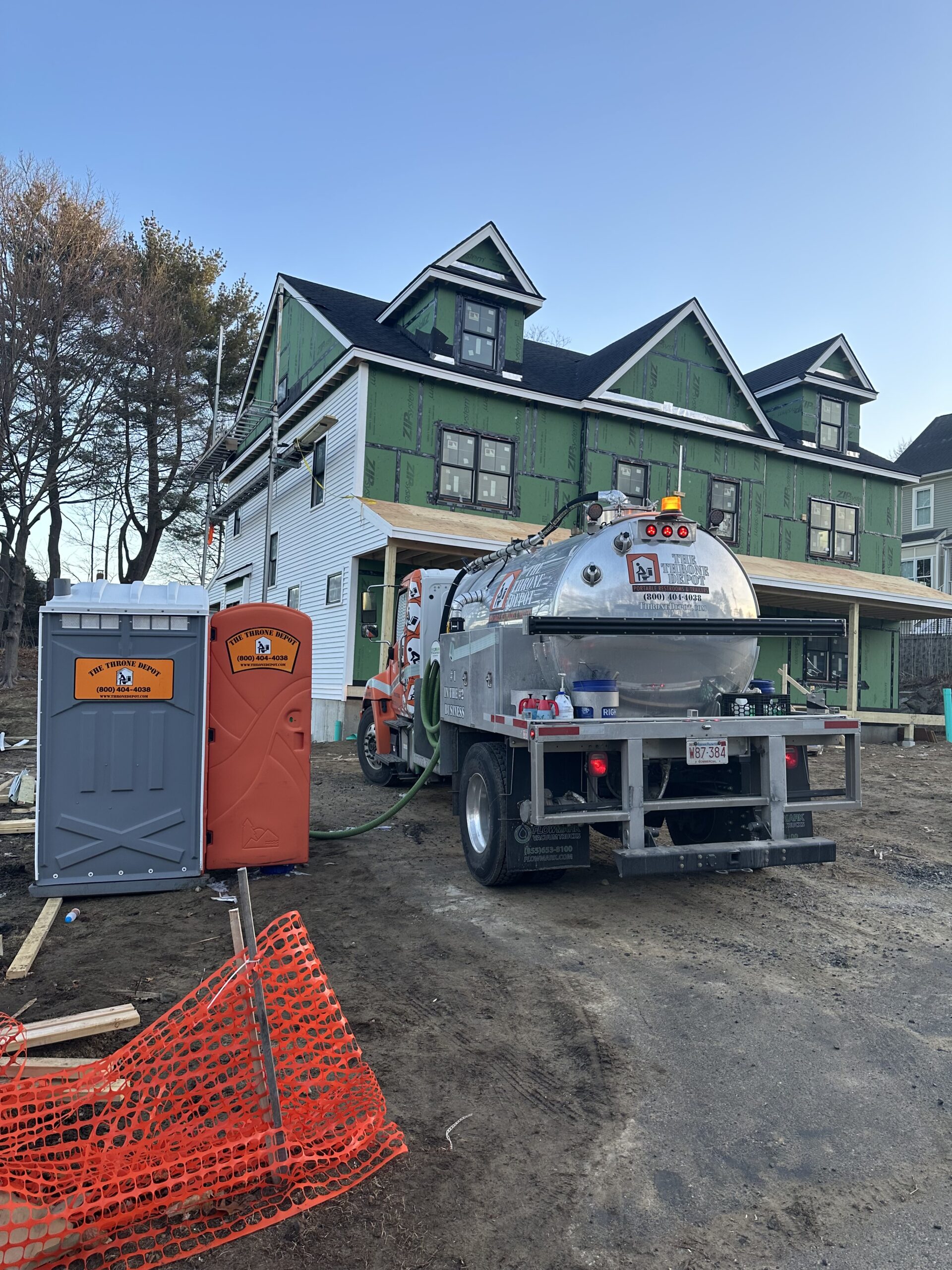 Service technician cleaning and restocking a portable toilet on an active construction site.